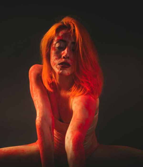 A woman performing a dynamic stretch exercise in a bright studio environment