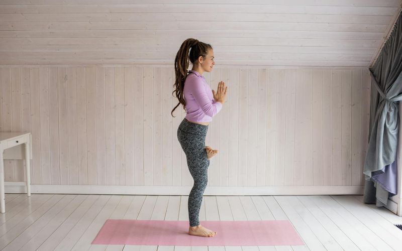 Person standing on one leg practicing balance on a sunset background